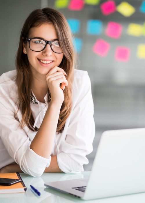 successful businesswoman working on laptop computer in her office dressed up in white strict clothes